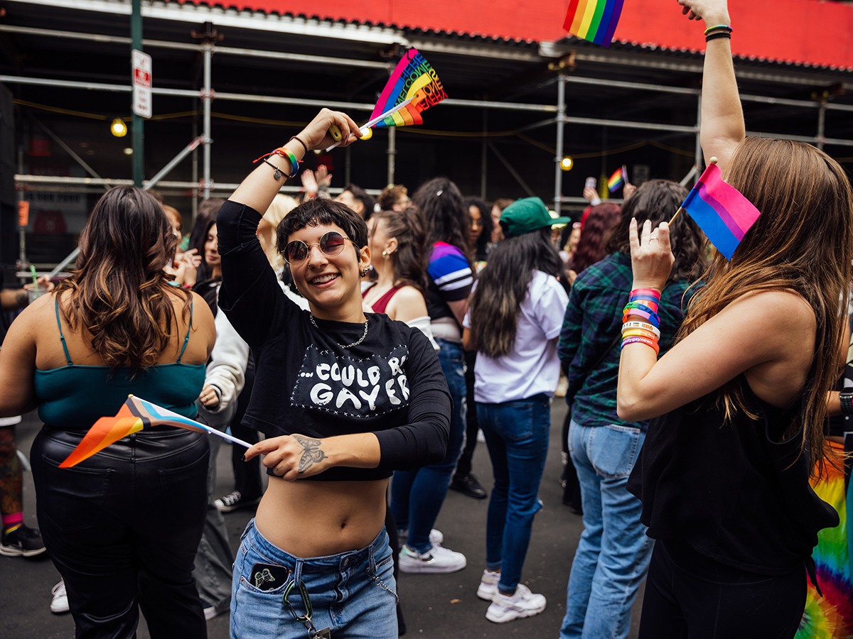 A joyful crowd at a Pride celebration waving rainbow and trans pride flags